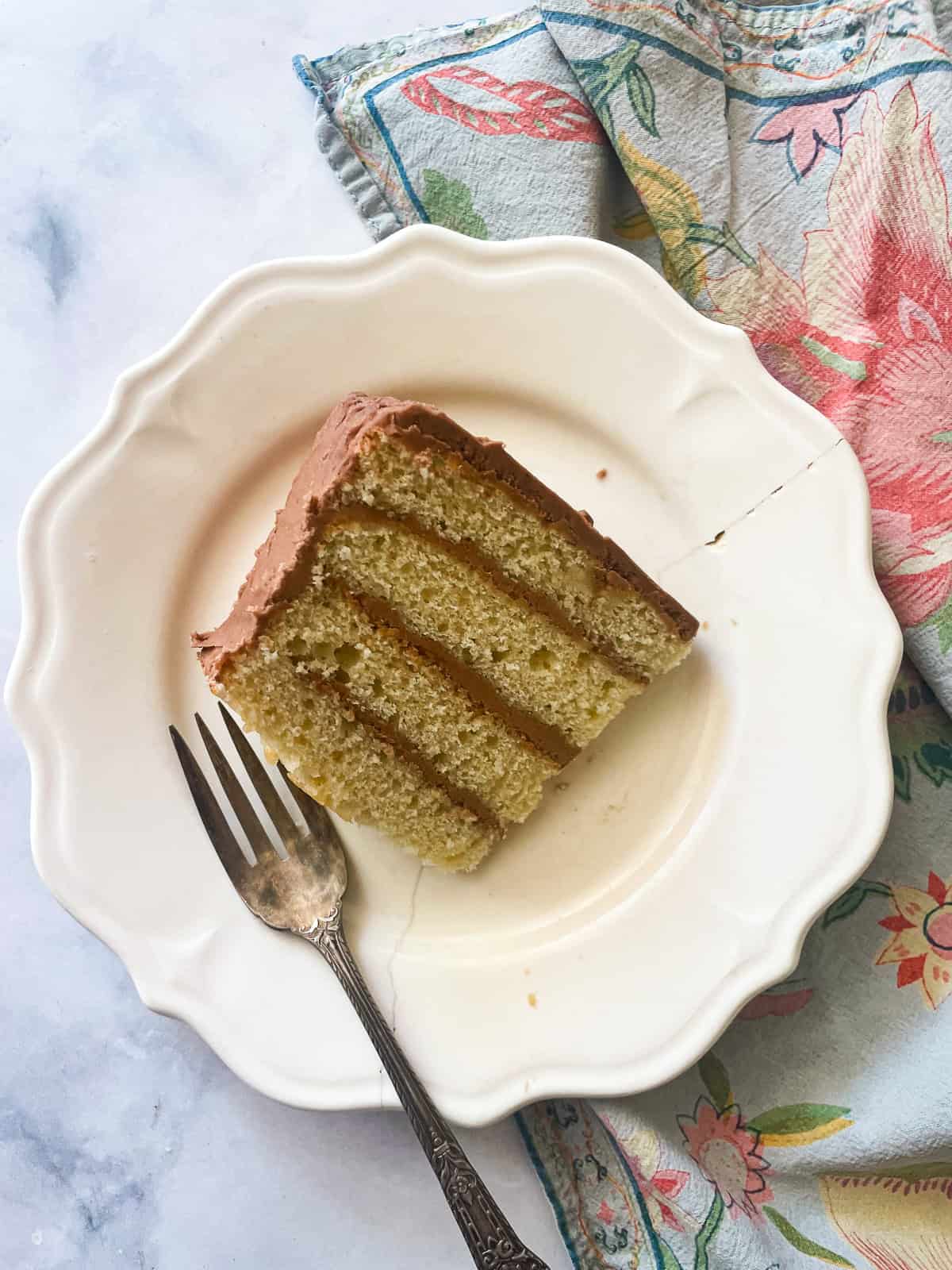 A slice of vanilla buttermilk cake on a plate with a fork.