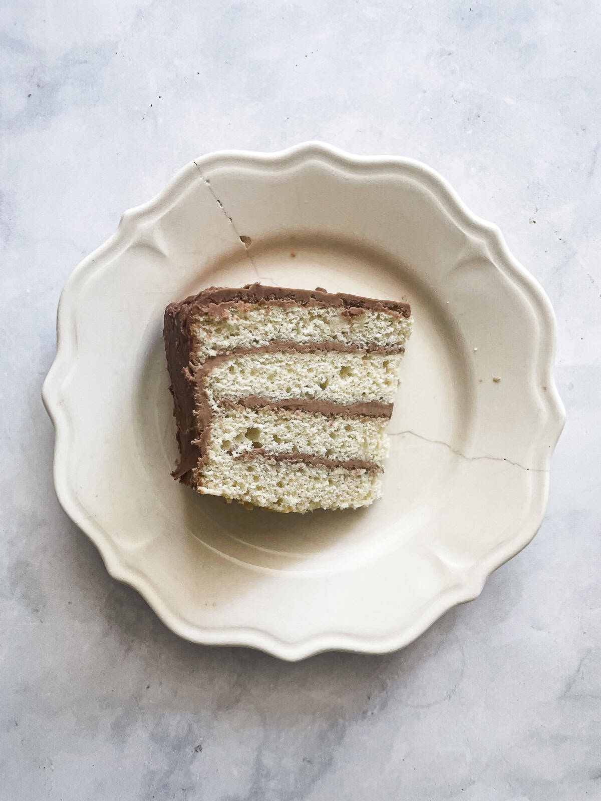 A slice of gluten free vanilla buttermilk cake with chocolate frosting.