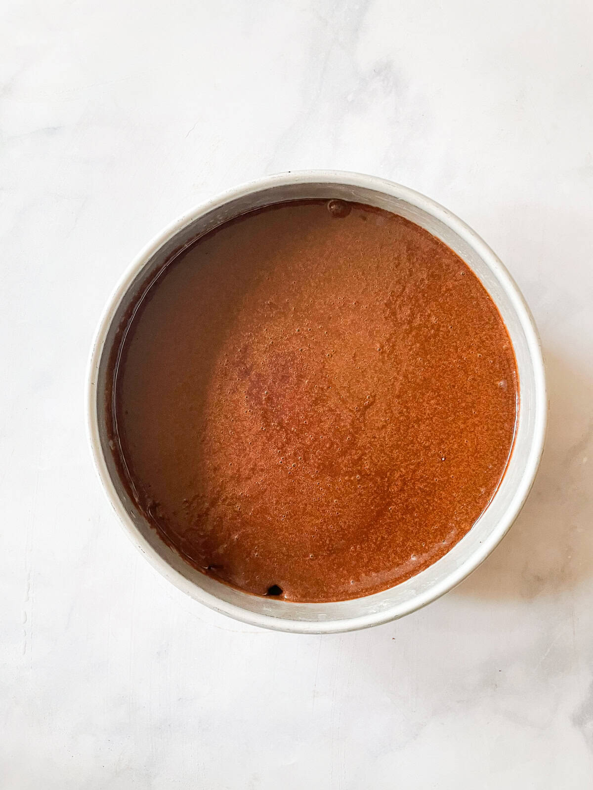 Chocolate teff cake batter in a cake pan.