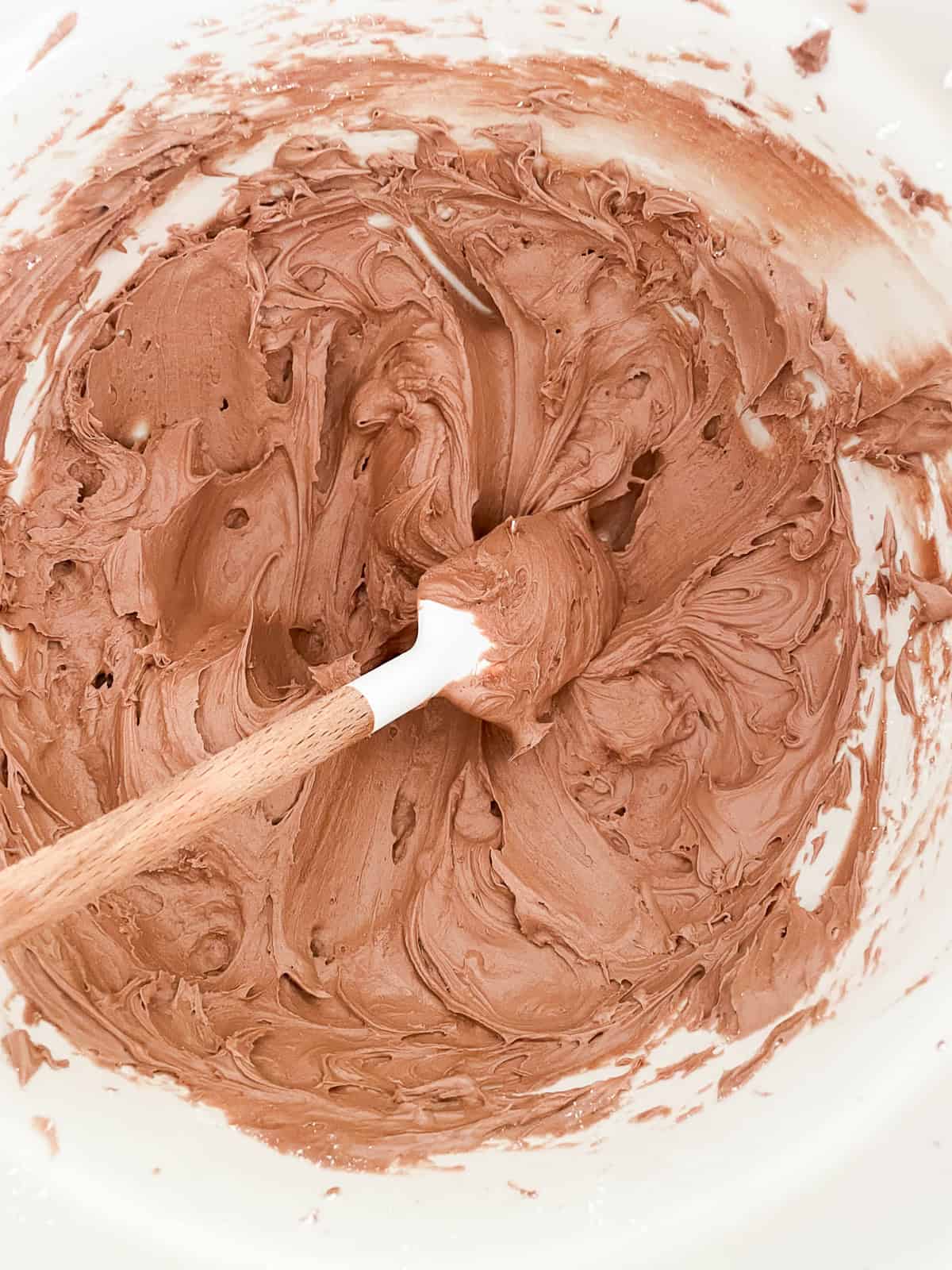 This beautiful gluten-free birthday cake recipe features velvety vanilla cake layers filled and frosted with chocolate buttercream frosting A bowl of chocolate buttercream.