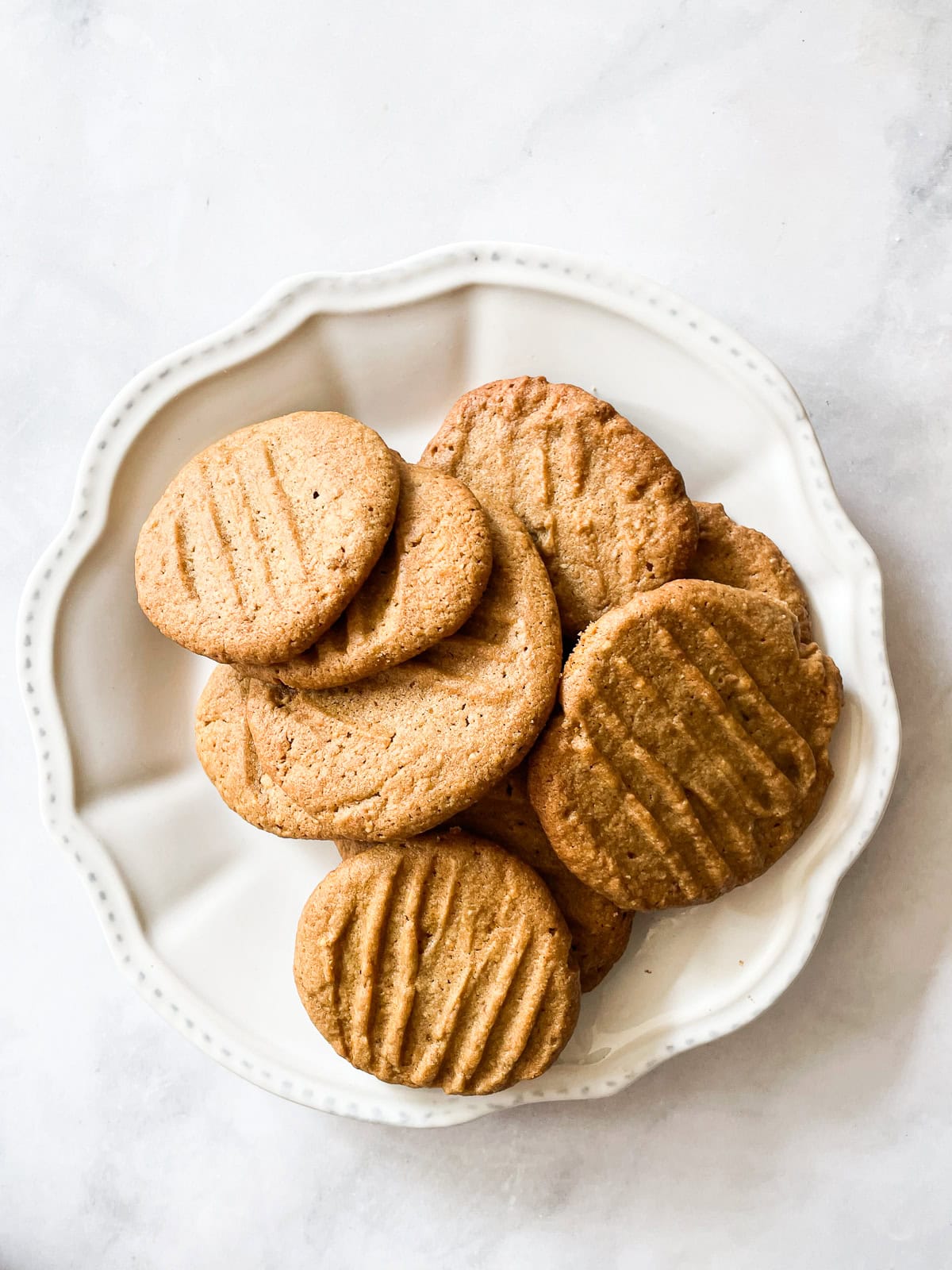 Tender oat flour peanut butter cookies are naturally gluten-free and packed with lots of fresh peanut butter. A one-bowl recipe! A white plate of oat flour peanut butter cookies.