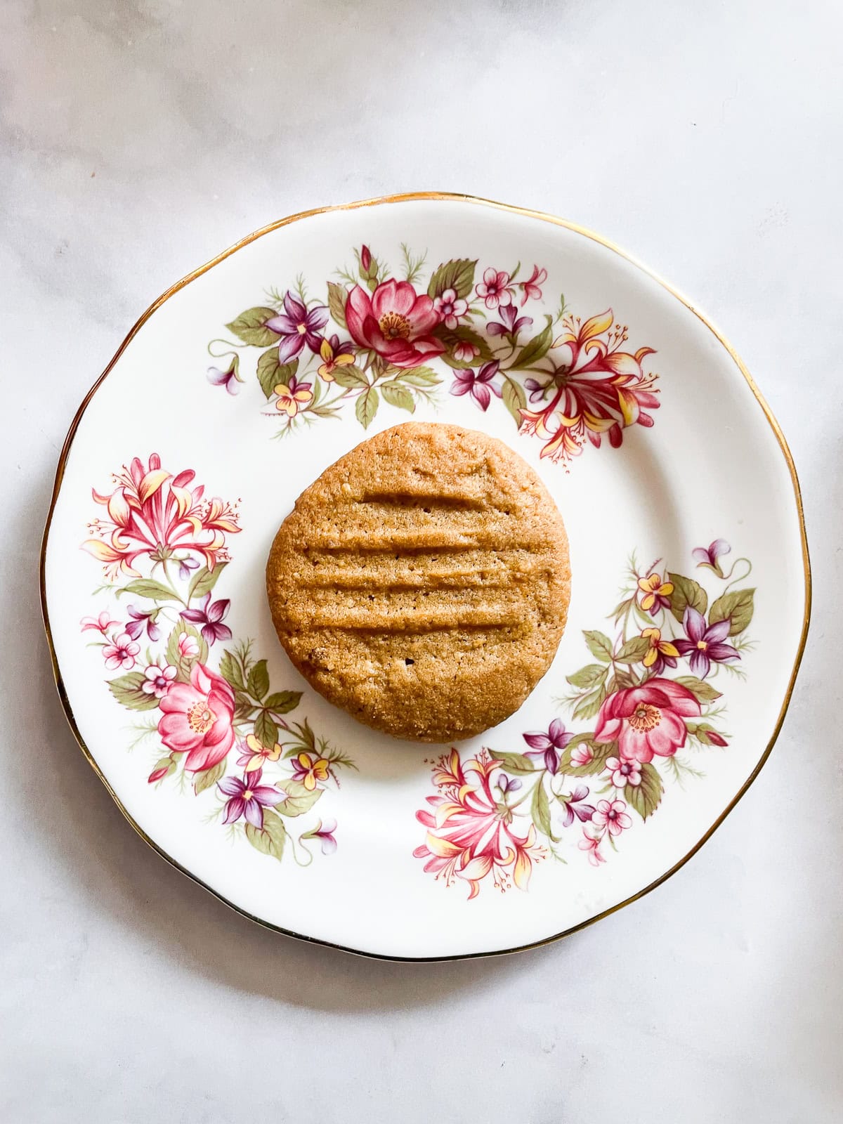 An oat flour peanut butter cookie on a flowered plate.