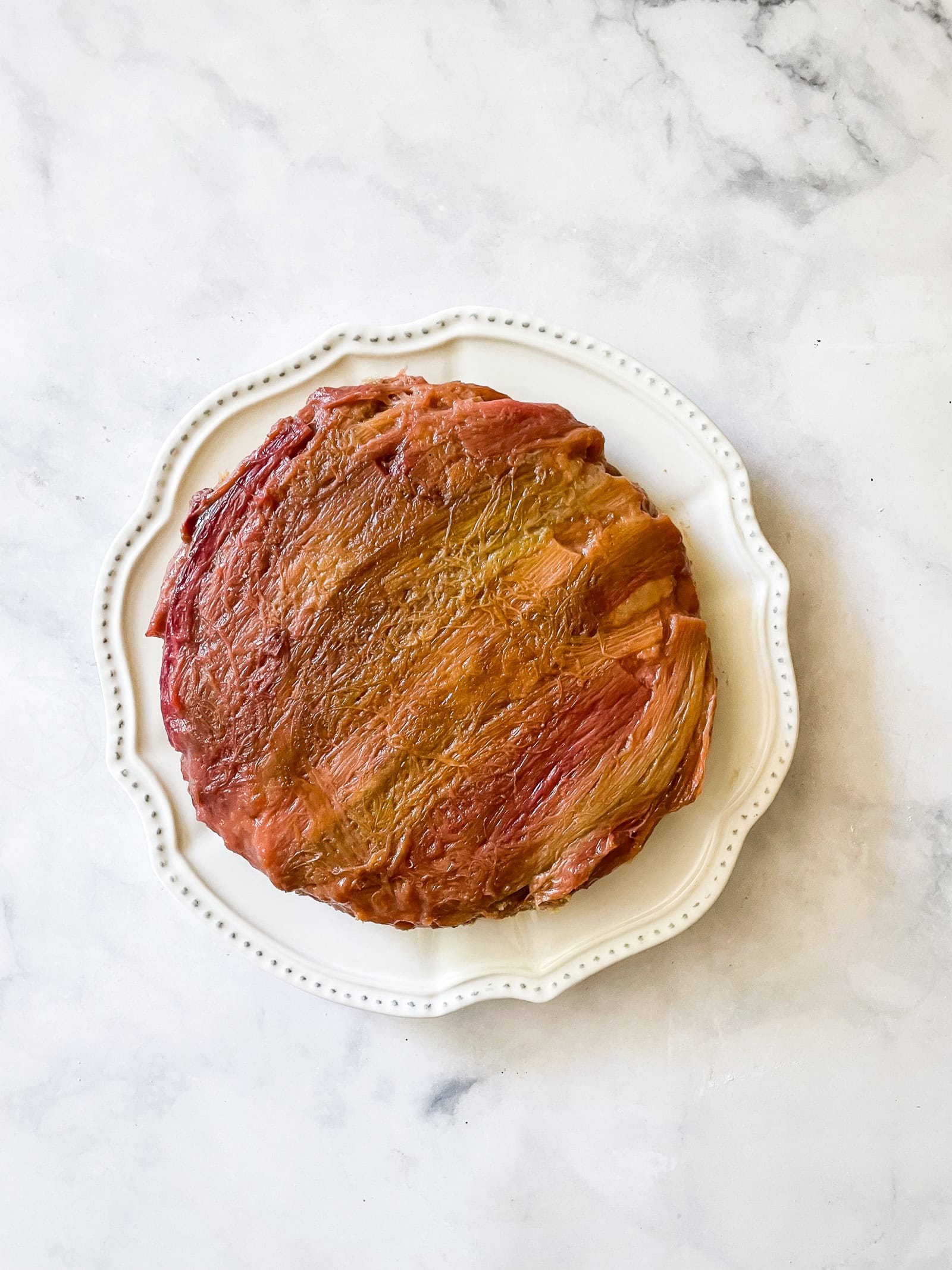 An upside-down rhubarb cake on a white plate.