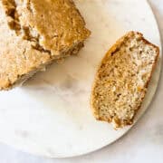 A loaf of gluten free coconut loaf cake with a slice cut from it.