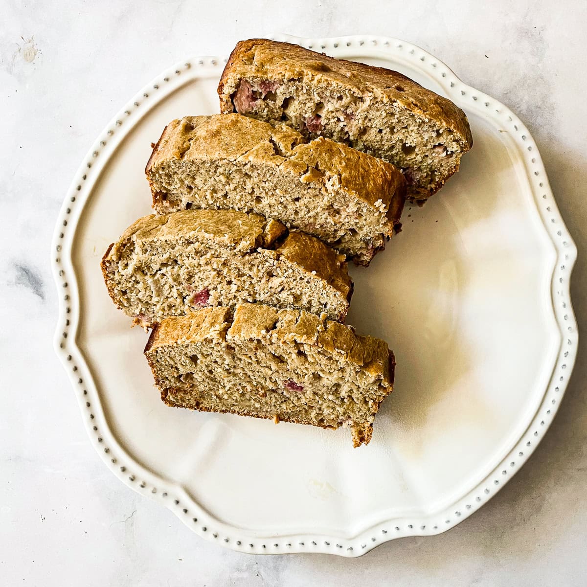 Slices of gluten free rhubarb banana bread on a white plate.