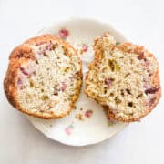 A gluten free strawberry muffin cut in half on a plate.
