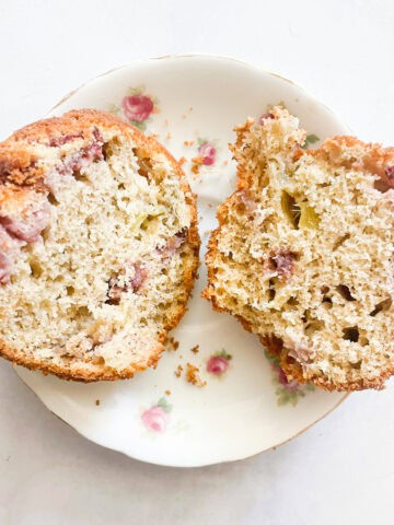 A gluten free strawberry muffin cut in half on a plate.