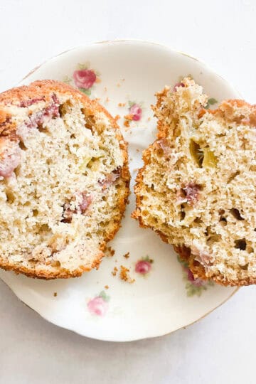 A gluten free strawberry muffin cut in half on a plate.
