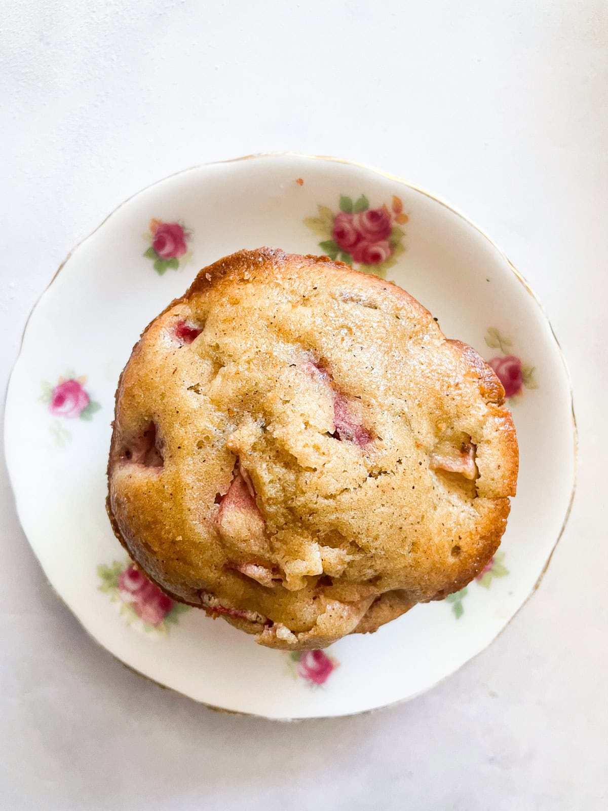 A gluten free strawberry muffin on a small flowered plate.