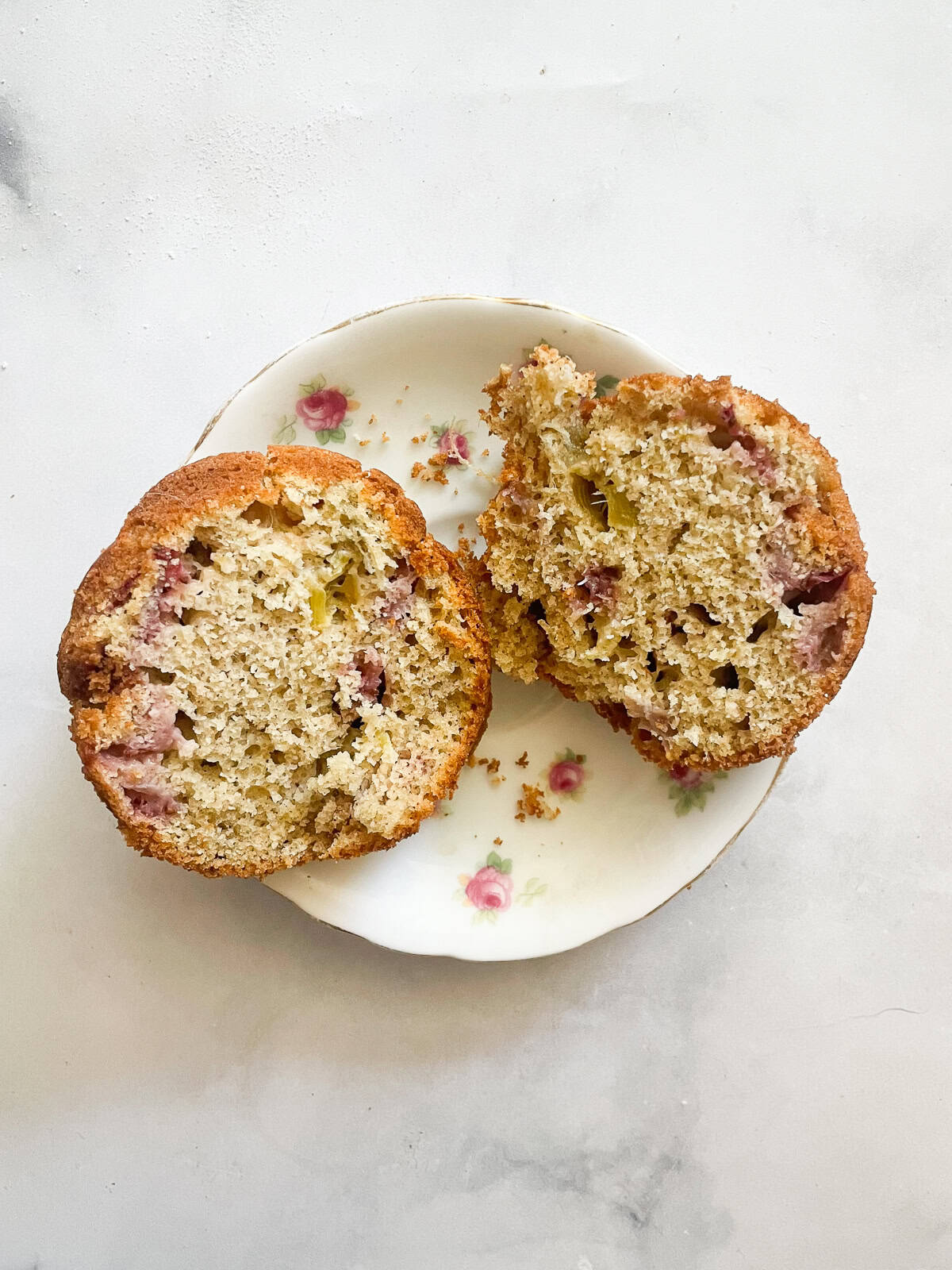 A gluten free strawberry muffin cut in half on a plate.