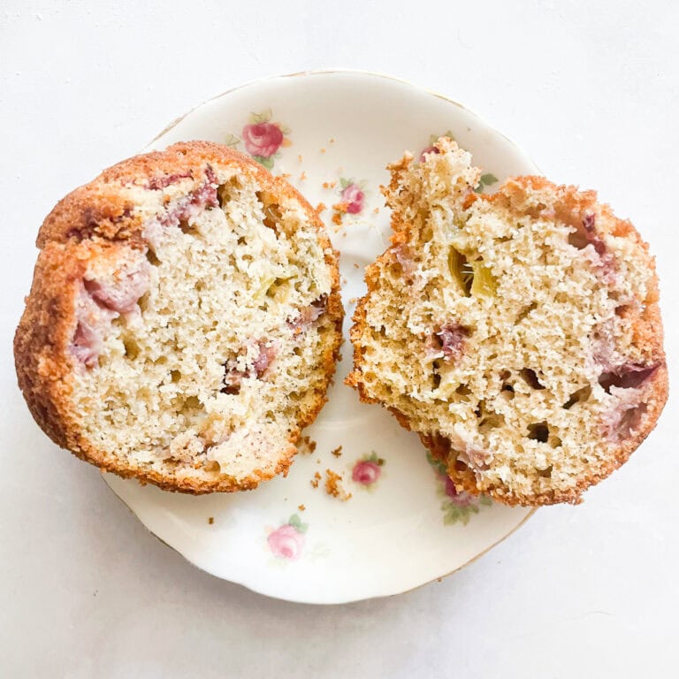 A gluten free strawberry muffin cut in half on a plate.