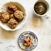 A bowl of vegan strawberry muffins, a muffin on a plate, and a cup of tea.