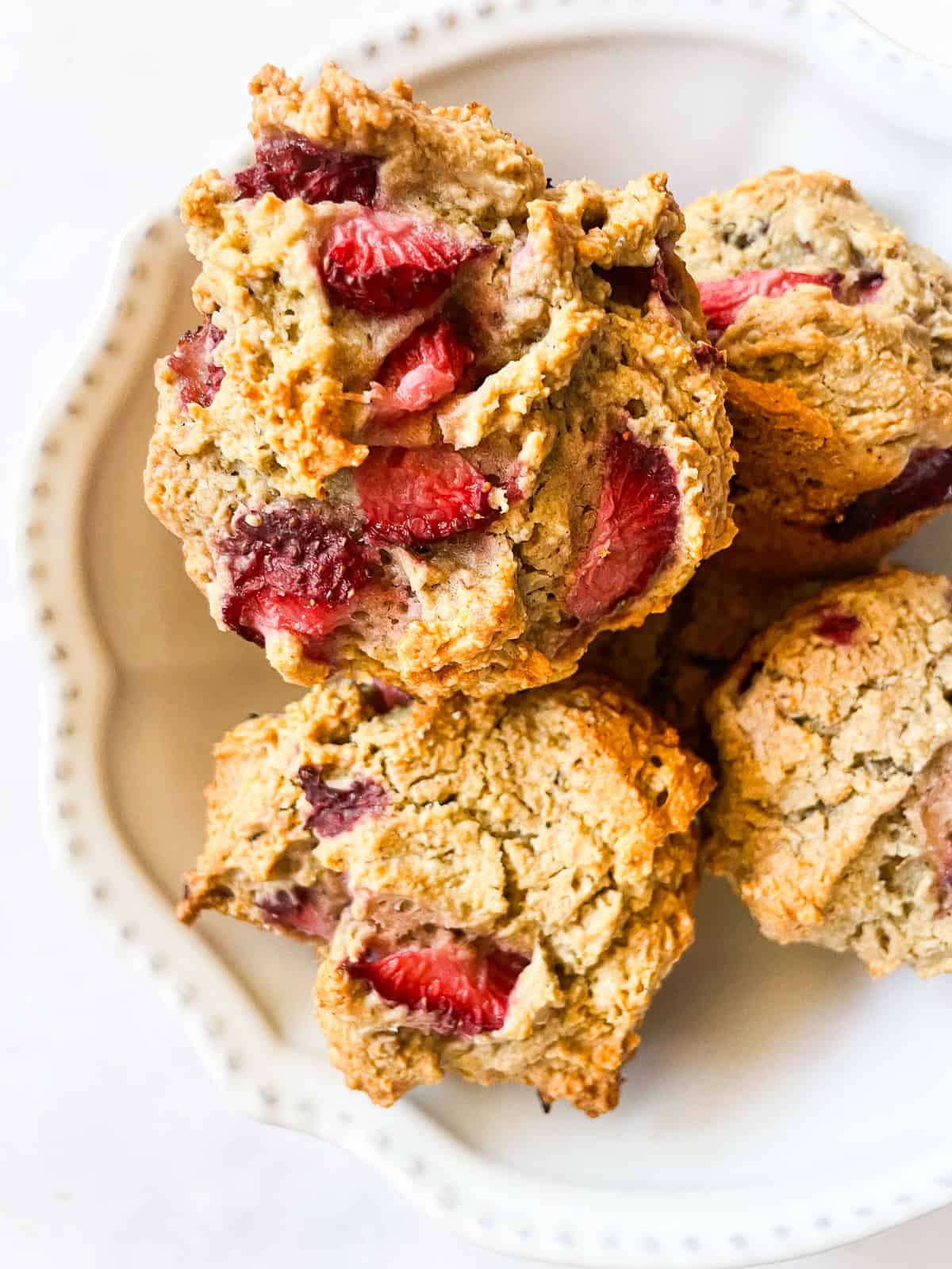 Lightly sweet and packed with fresh strawberries, these gluten free and vegan strawberry muffins are so lovely and tender. Strawberries are seen on vegan strawberry muffins in a bowl.