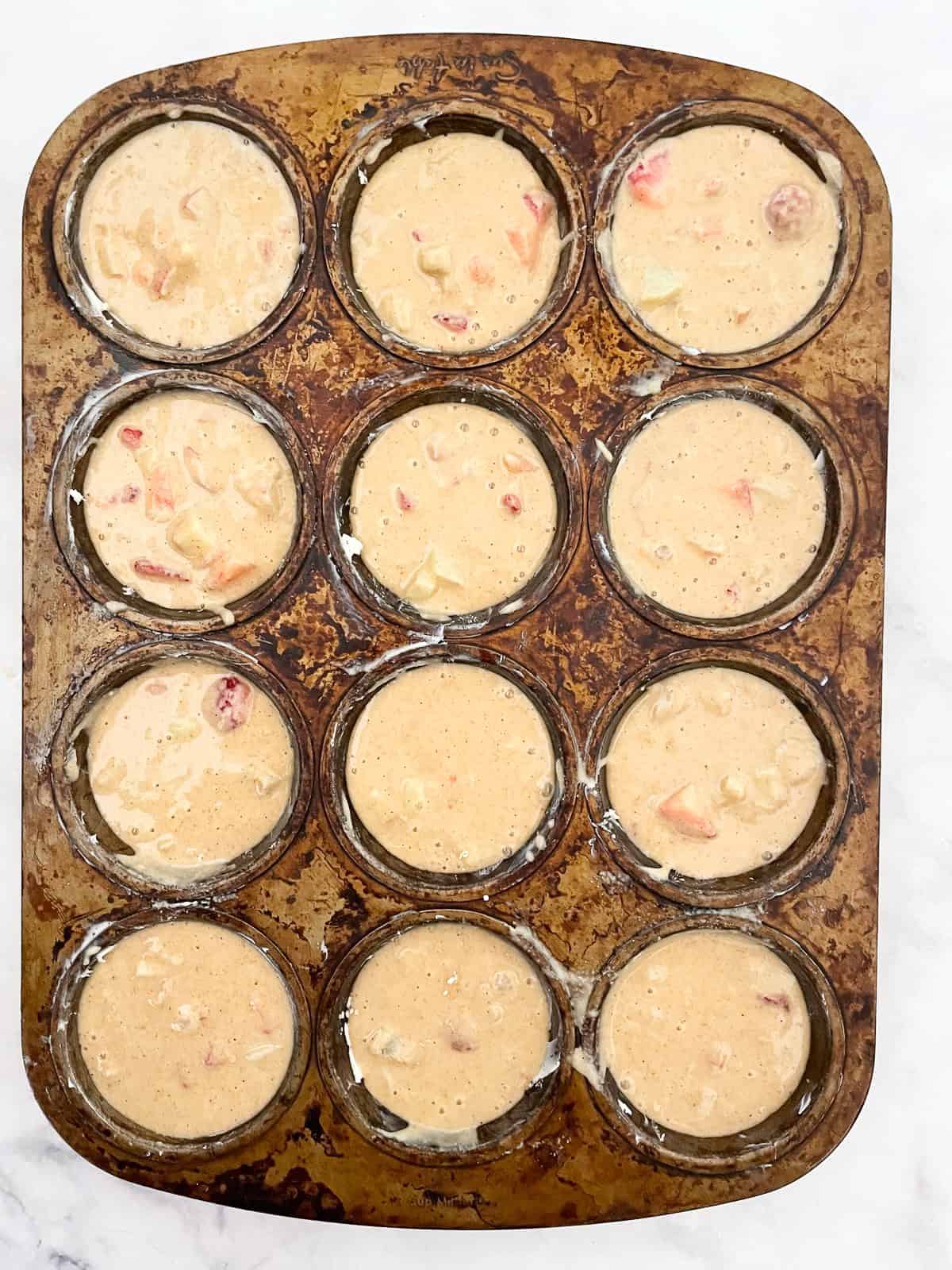 Gluten free strawberry muffin batter in a muffin tin.
