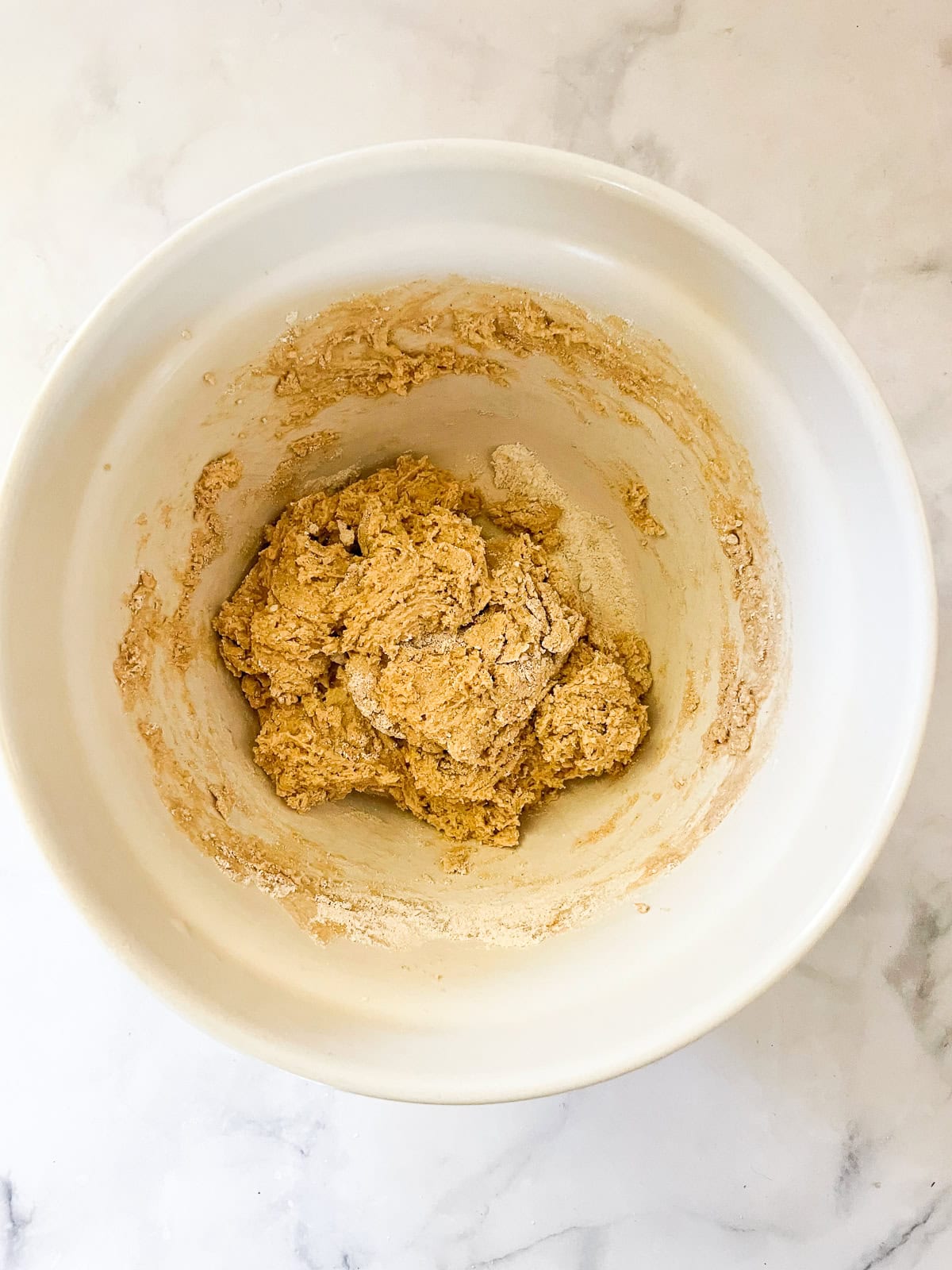 Dry ingredients are added to wet ingredients for vegan strawberry muffins.