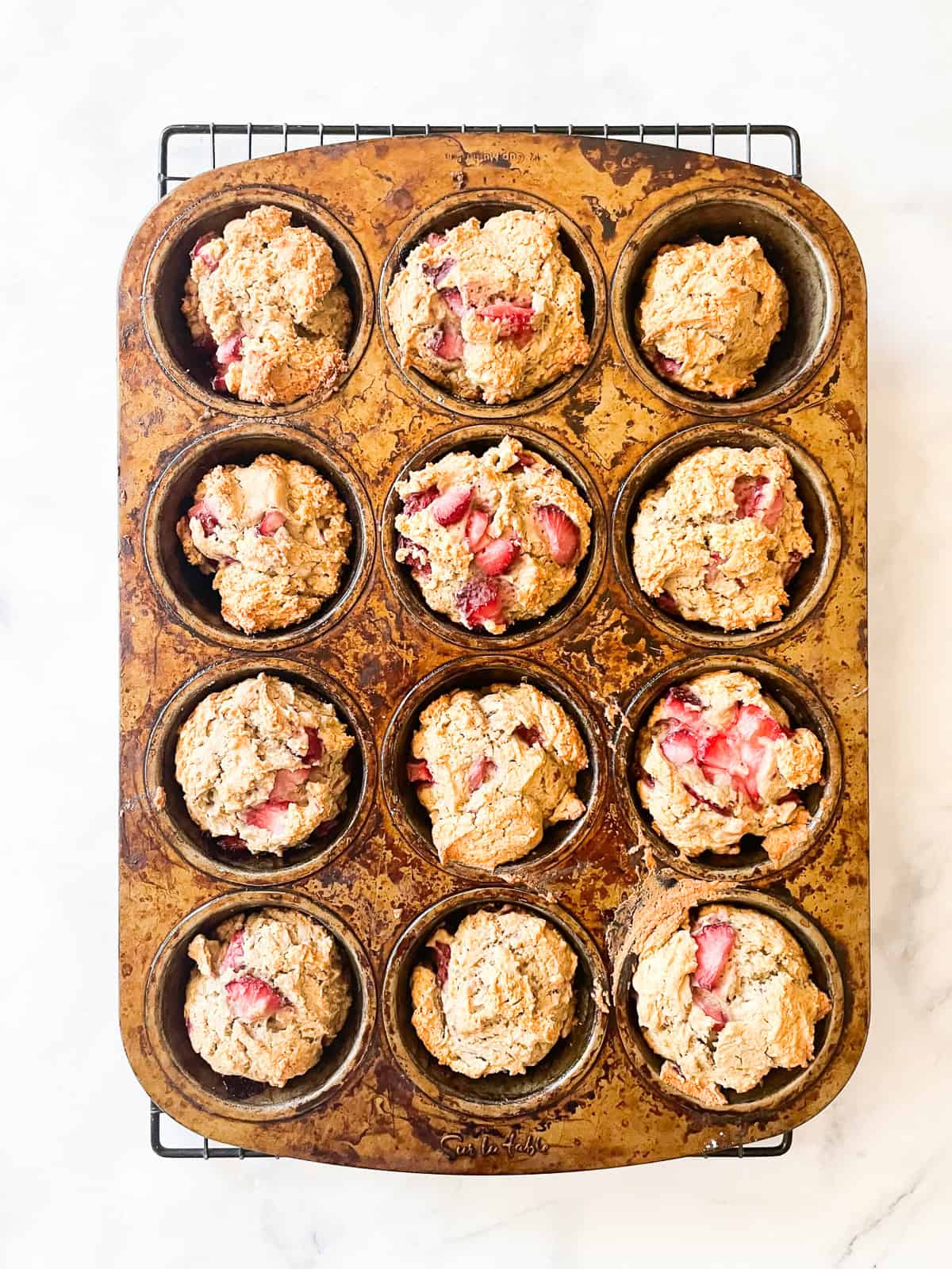 Vegan strawberry muffins cool in the muffin tin.