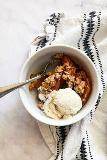 A bowl of any fruit crisp topped with ice cream.