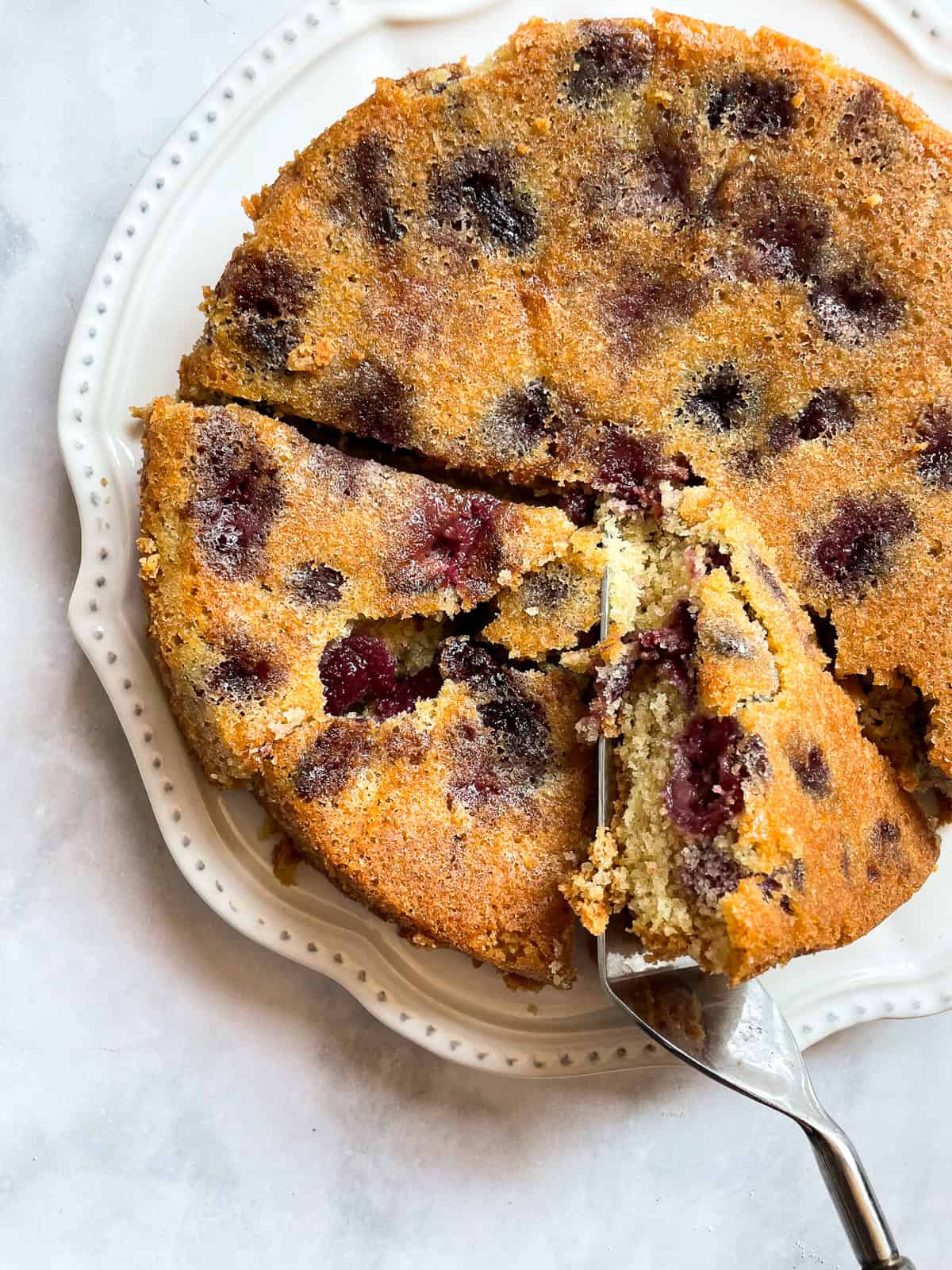 A slice of gluten free cherry torte is turned on its side to show its interior.