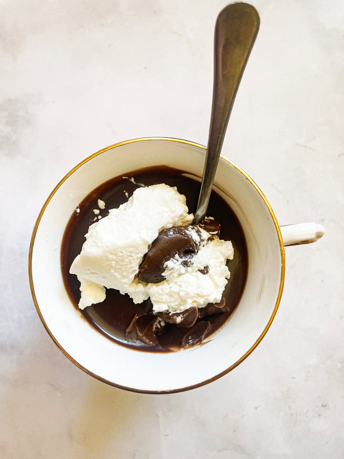 Silky smooth and wonderfully rich gluten free chocolate pudding comes together easily to make a celebration-worthy dessert. A tea cup of gluten free chocolate pudding and whipped cream with a spoon.