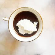 A tea cup of gluten free chocolate pudding topped with whipped cream.
