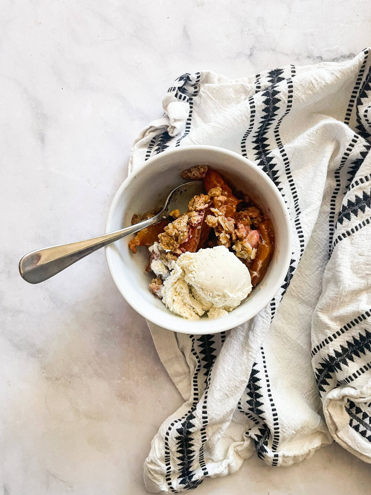 This gluten-free peach crisp stars juicy fresh peaches tucked under a rich toasted oat topping. Must be served with vanilla ice cream! Vanilla ice cream is perfect on top of a warm bowl of gluten-free peach crisp.