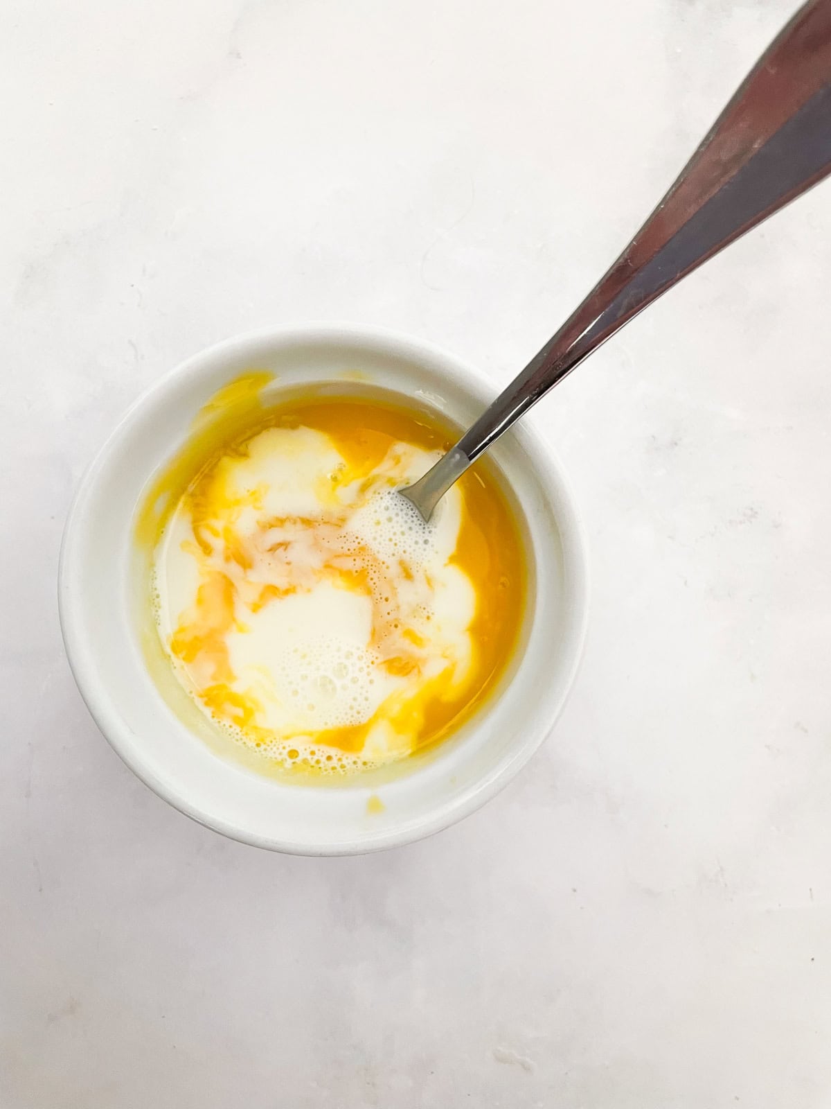 Silky smooth and wonderfully rich gluten free chocolate pudding comes together easily to make a celebration-worthy dessert. A spoon mixes hot cream into egg yolks to temper them.
