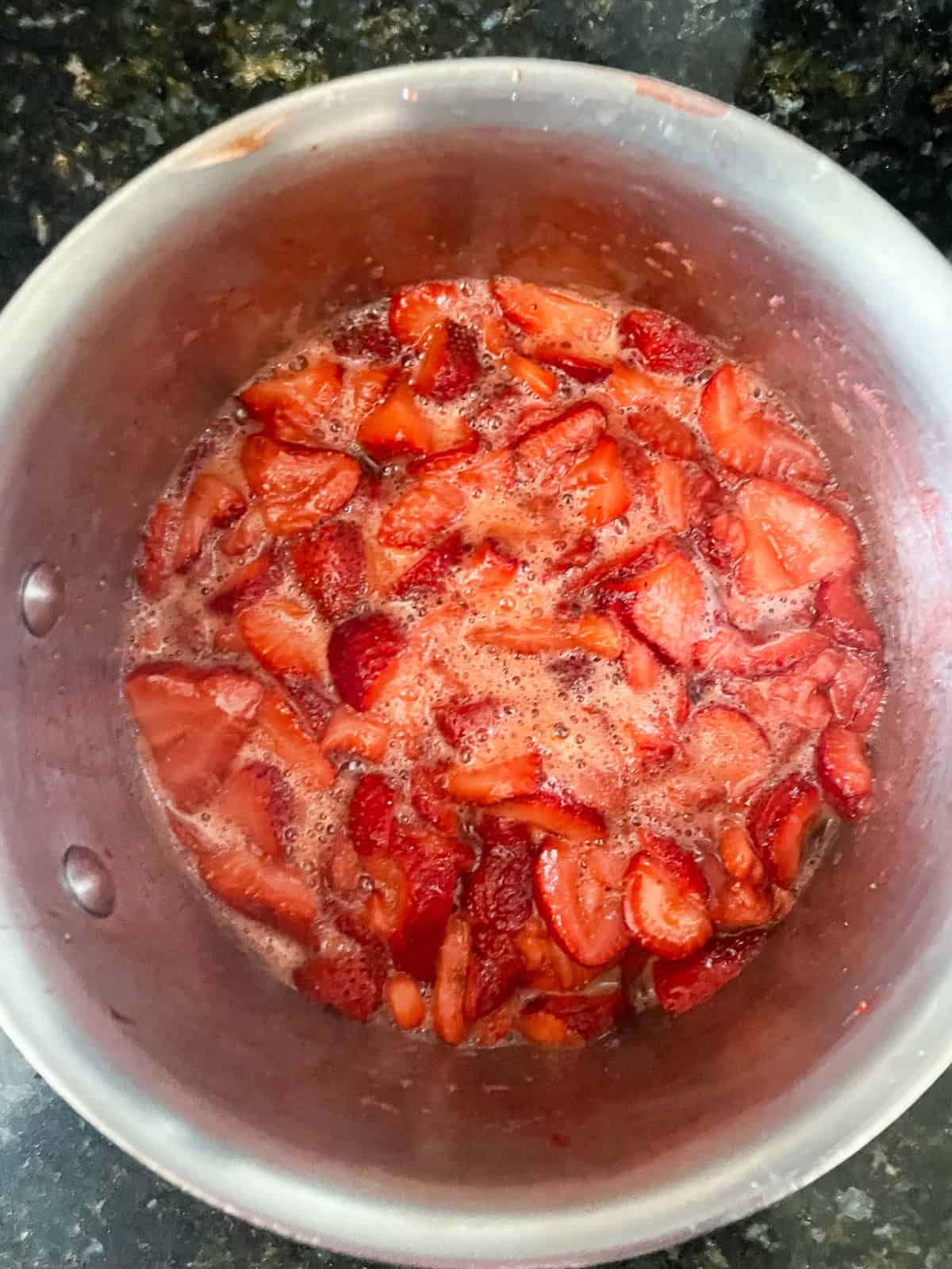 A recipe for a beautifully hued, low sugar strawberry jam that's also made without pectin. You can make this a refrigerator jam or can it. Strawberry jam at the first stage of cooking in a pot.