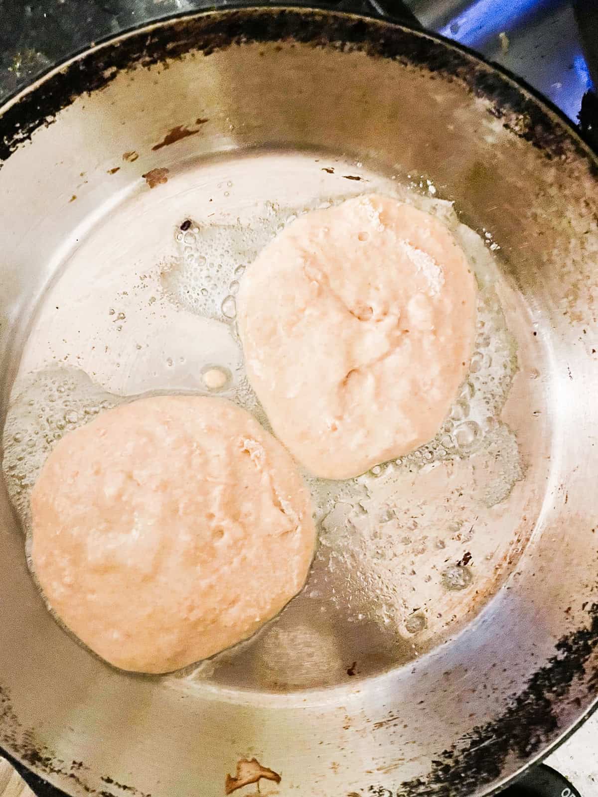 Tender and fluffy oat flour pancakes are made with oat flour for a gorgeous, naturally gluten-free breakfast option. A one-bowl recipe! Two oat flour pancakes cook in a skillet.