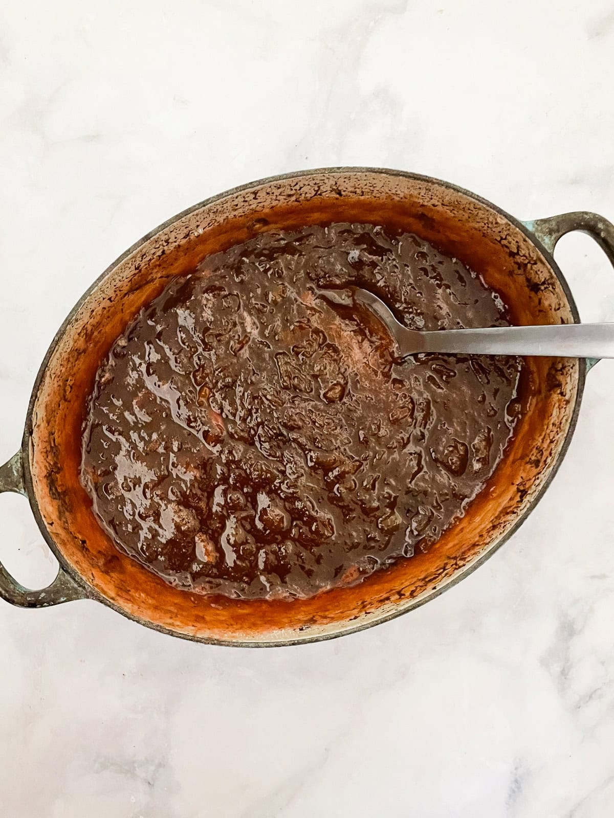 A pretty raspberry rhubarb jam that marries seasonal fresh berries with tart rhubarb to make a silky smooth, uniquely flavored jam. Raspberry rhubarb jam with a spoon in it.
