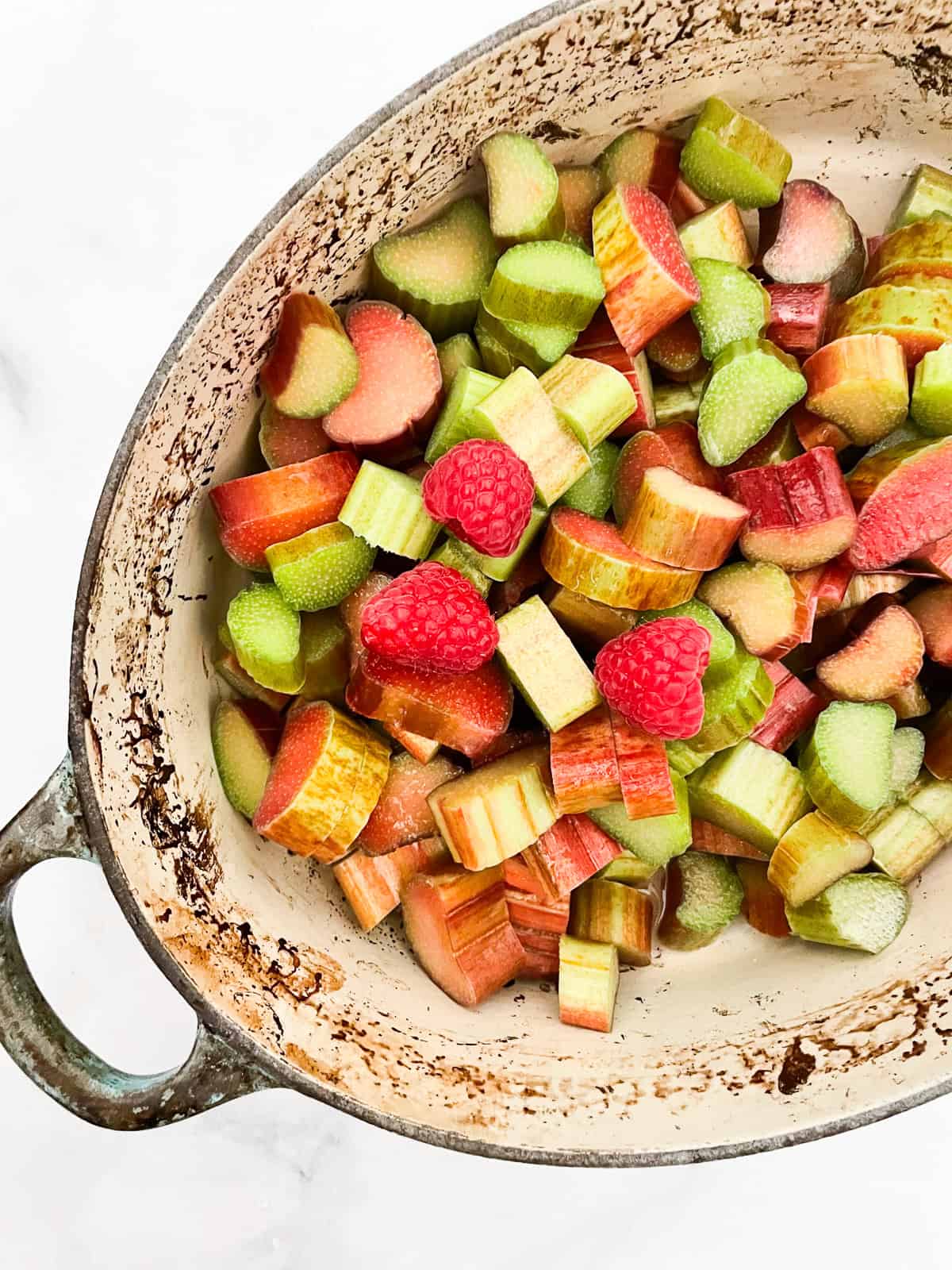 A pretty raspberry rhubarb jam that marries seasonal fresh berries with tart rhubarb to make a silky smooth, uniquely flavored jam. Raspberries and rhubarb in a pot.