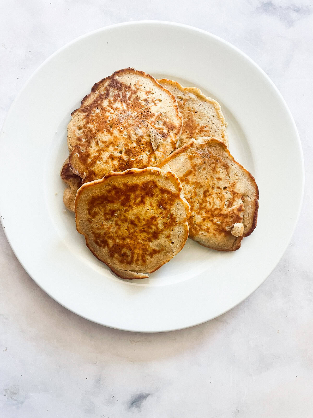 A white plate with fried oat flour pancakes.