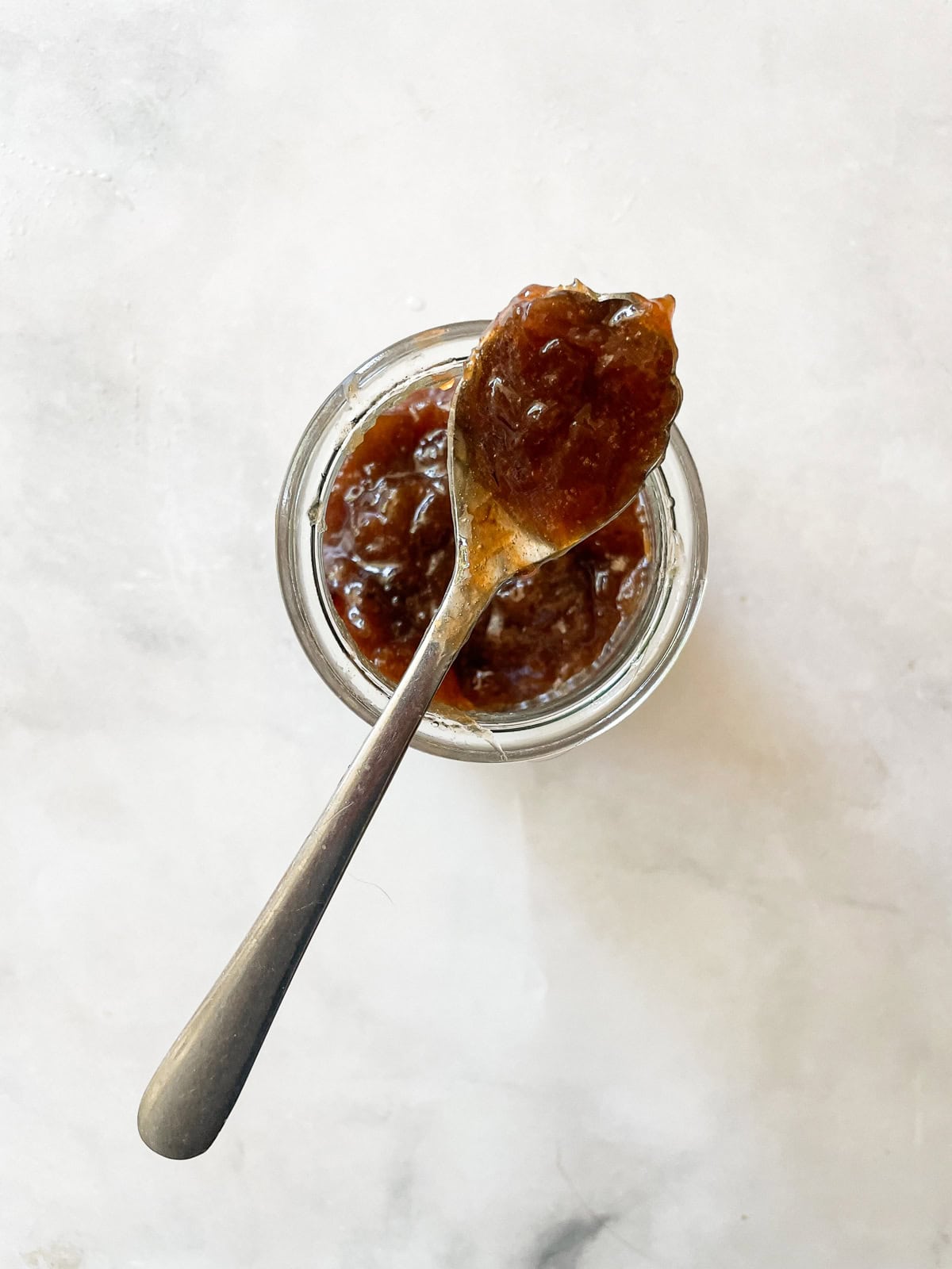 A pretty raspberry rhubarb jam that marries seasonal fresh berries with tart rhubarb to make a silky smooth, uniquely flavored jam. Raspberry rhubarb jam on a spoon.