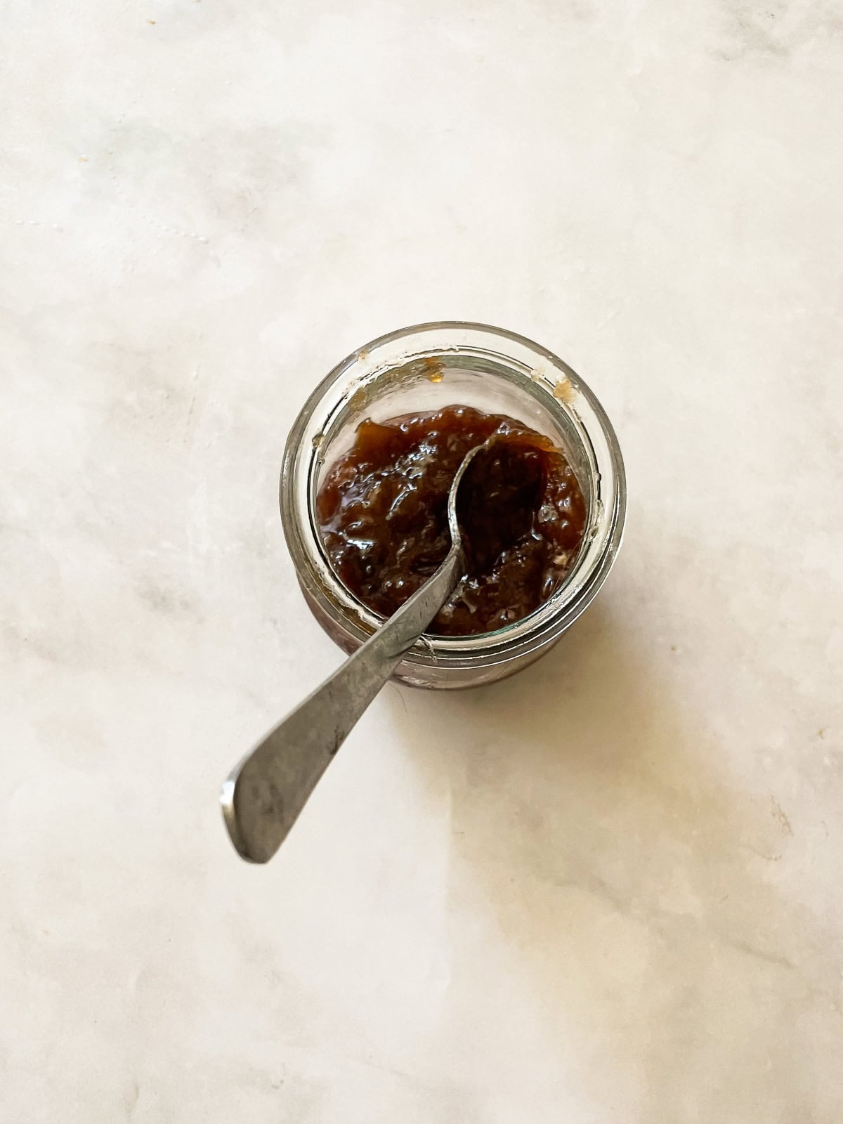 A pretty raspberry rhubarb jam that marries seasonal fresh berries with tart rhubarb to make a silky smooth, uniquely flavored jam. A spoon rests in a jar of raspberry rhubarb jam.
