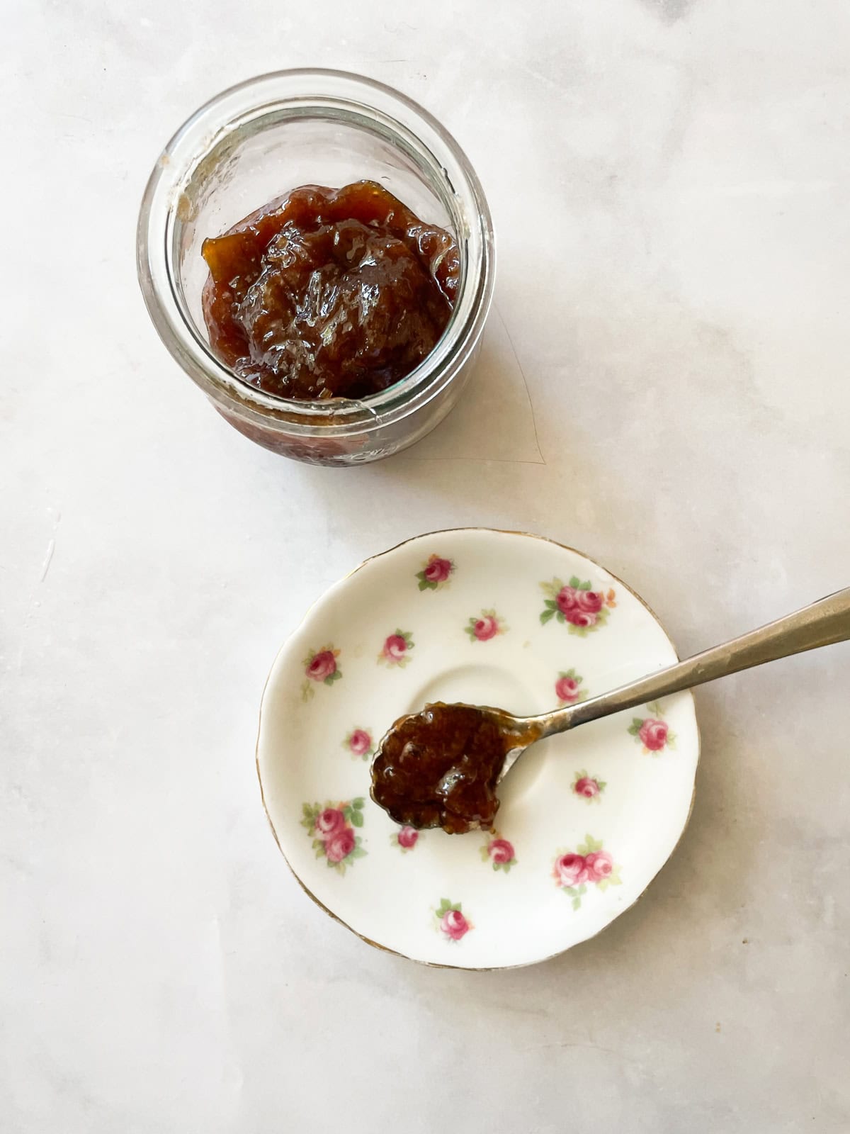 A jar of rhubarb jam and a spoonful of jam on a pretty plate.