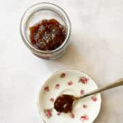 A jar of rhubarb jam and a spoonful of jam on a pretty plate.