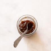 A jar of rhubarb jam with honey and a spoon.