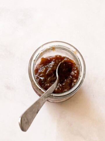 A jar of rhubarb jam with honey and a spoon.