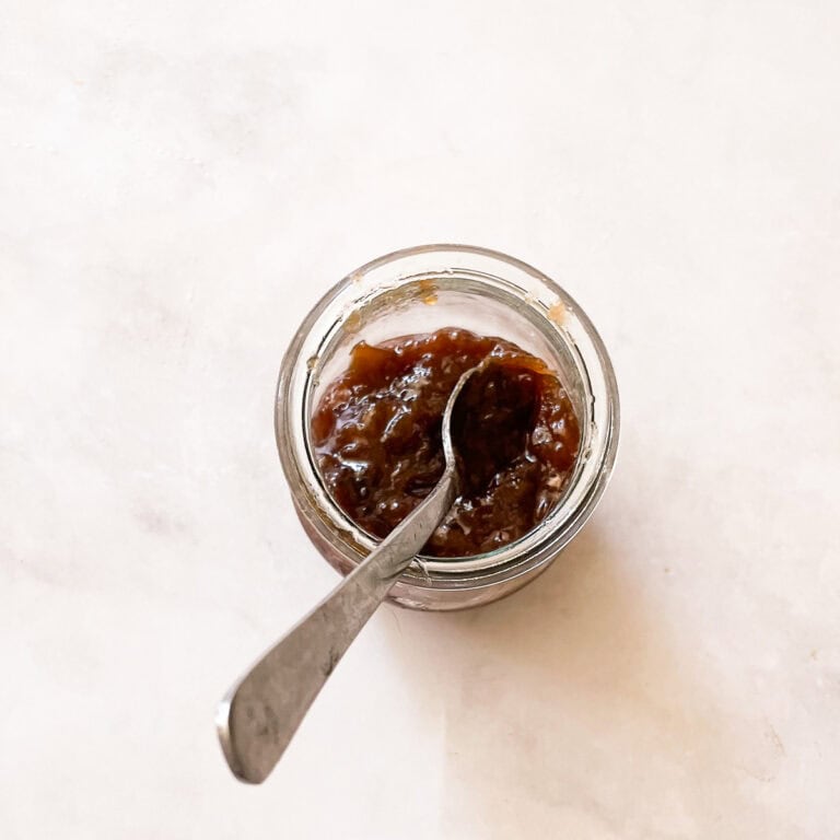 A jar of rhubarb jam with honey and a spoon.