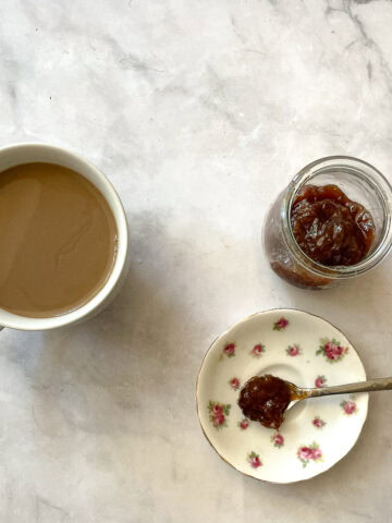 A cup of coffee and a plate with strawberry rhubarb freezer jam.