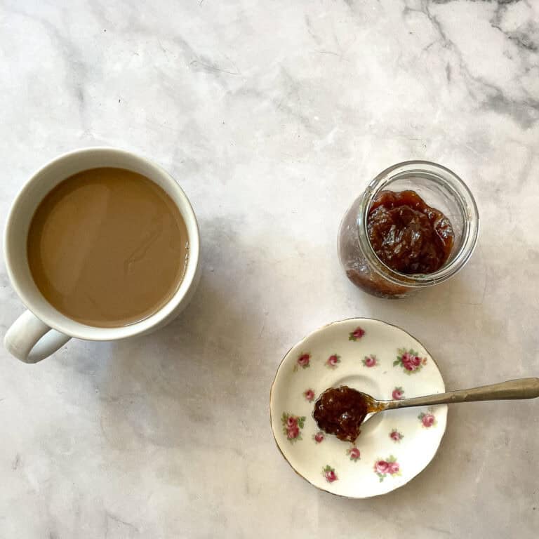 A cup of coffee and a plate with strawberry rhubarb freezer jam.