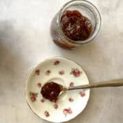 A jar of strawberry rhubarb freezer jam and a spoonful of jam on a plate.
