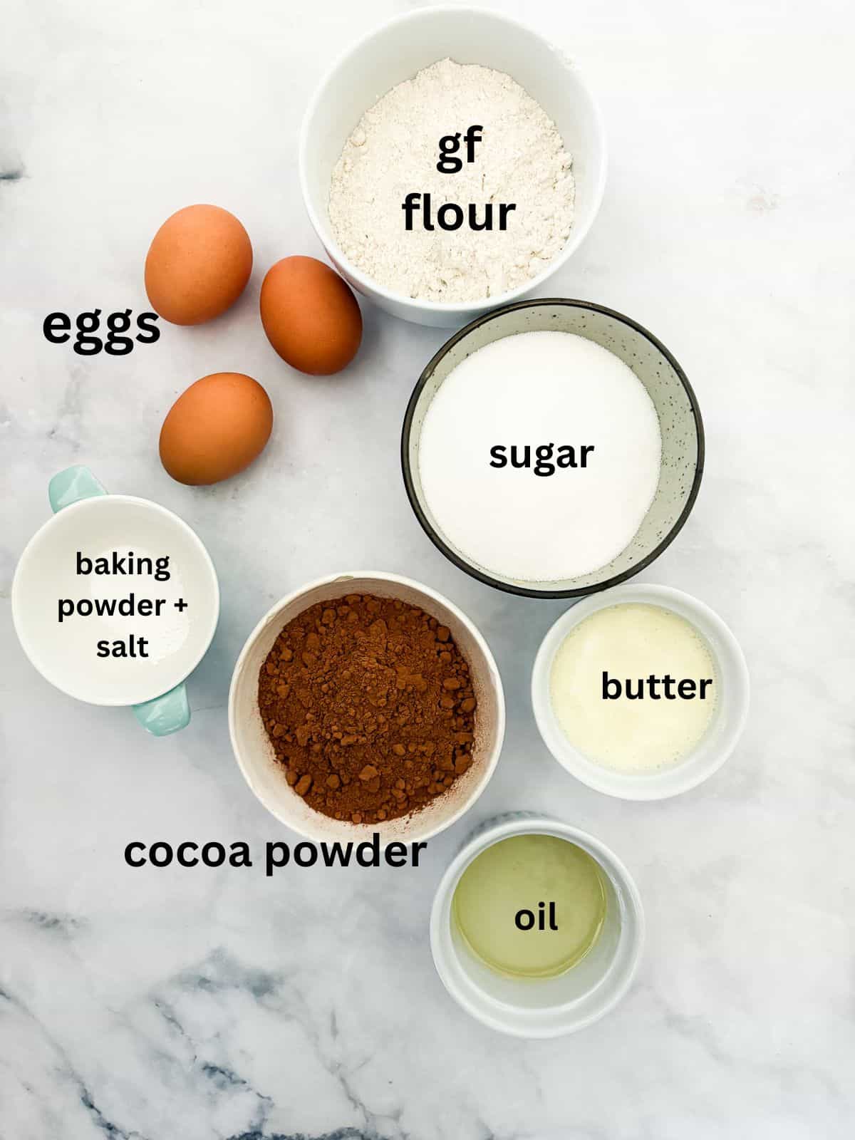 Effortless and gluten-free one bowl brownies are made in, yep, just one bowl. Just mix, pour, and bake to brownie perfection. The ingredients for gluten free one bowl brownies are text labeled and portioned out.