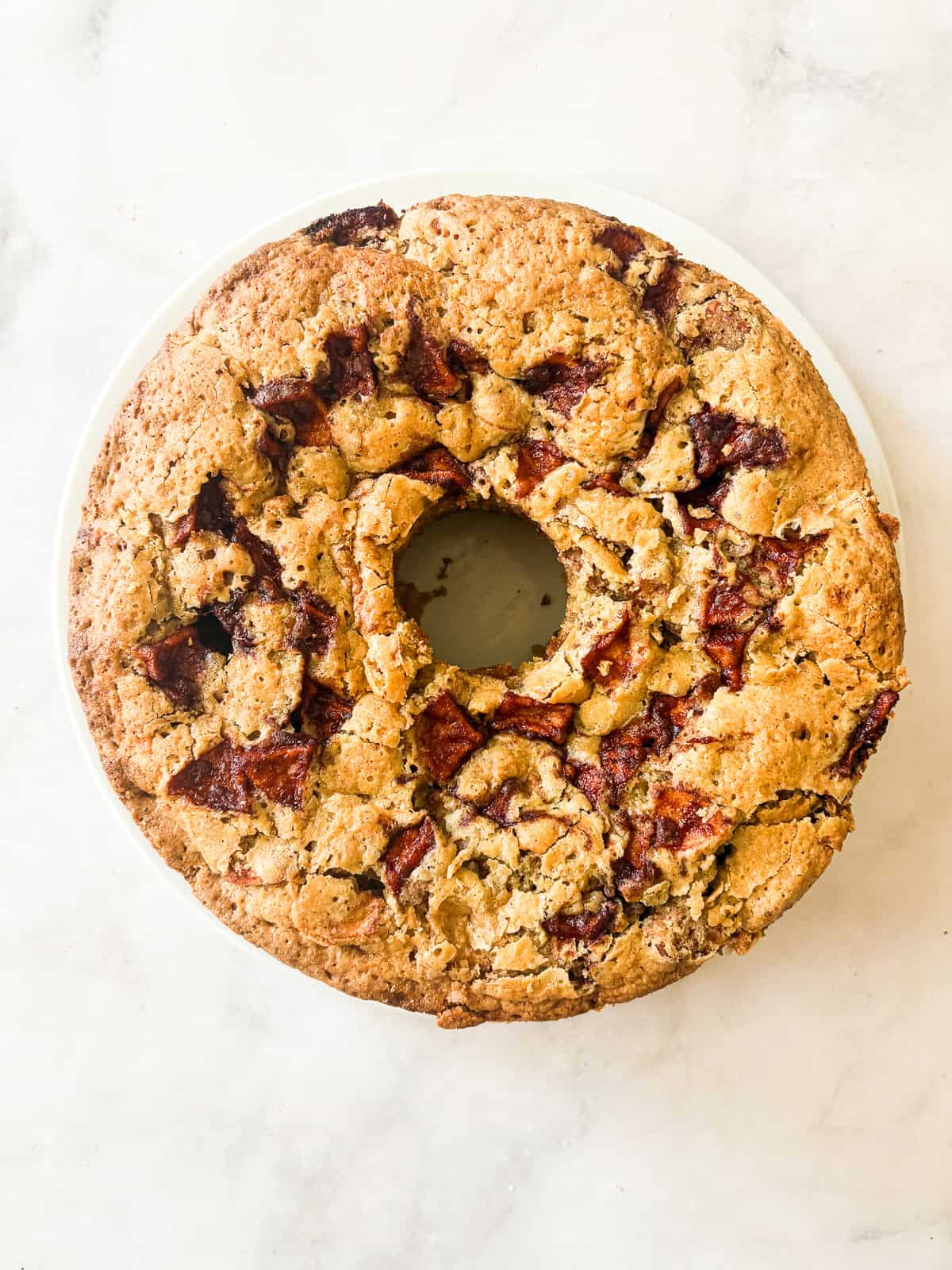 A sweet and simple gluten free apple cake that showcases a tender cake layered with cinnamon-y apples. One-bowl recipe! A gluten free apple cake on a plate.