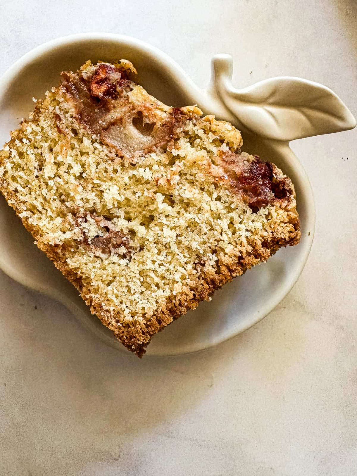 A sweet and simple gluten free apple cake that showcases a tender cake layered with cinnamon-y apples. One-bowl recipe! A little apple shaped plate with a slice of apple cake on it.