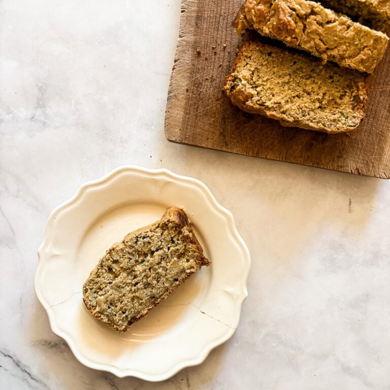 A sliced loaf of gluten free banana & zucchini bread with a slice on a plate.