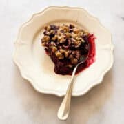 A serving of gluten free blackberry crisp on a a plate with a spoon.