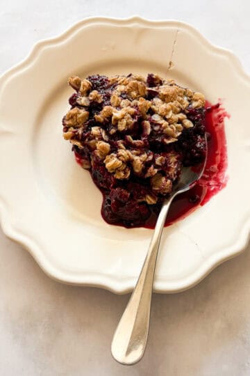 A serving of gluten free blackberry crisp on a a plate with a spoon.