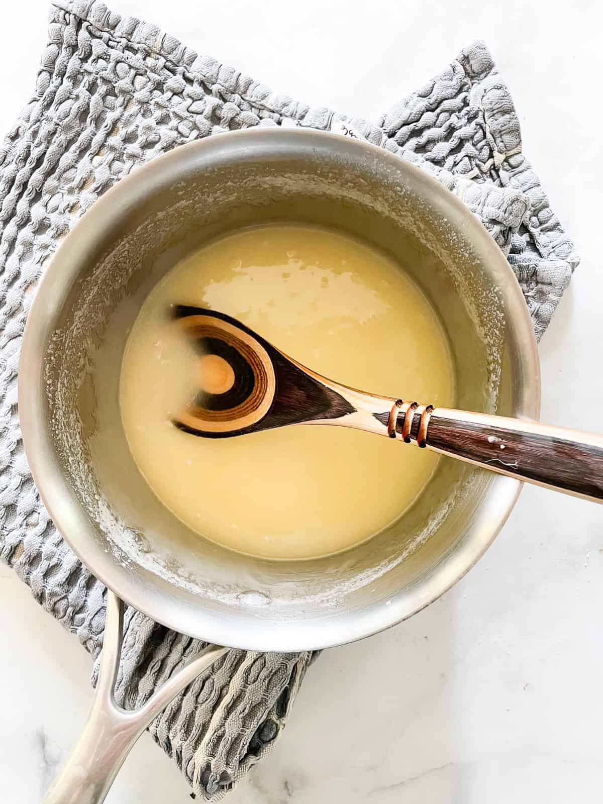 Fudgy gluten free brownies are loaded with chocolatey goodness! Minimal ingredients come together to make the best-ever homemade brownies. Butter and sugar melted in a pot with a spoon.