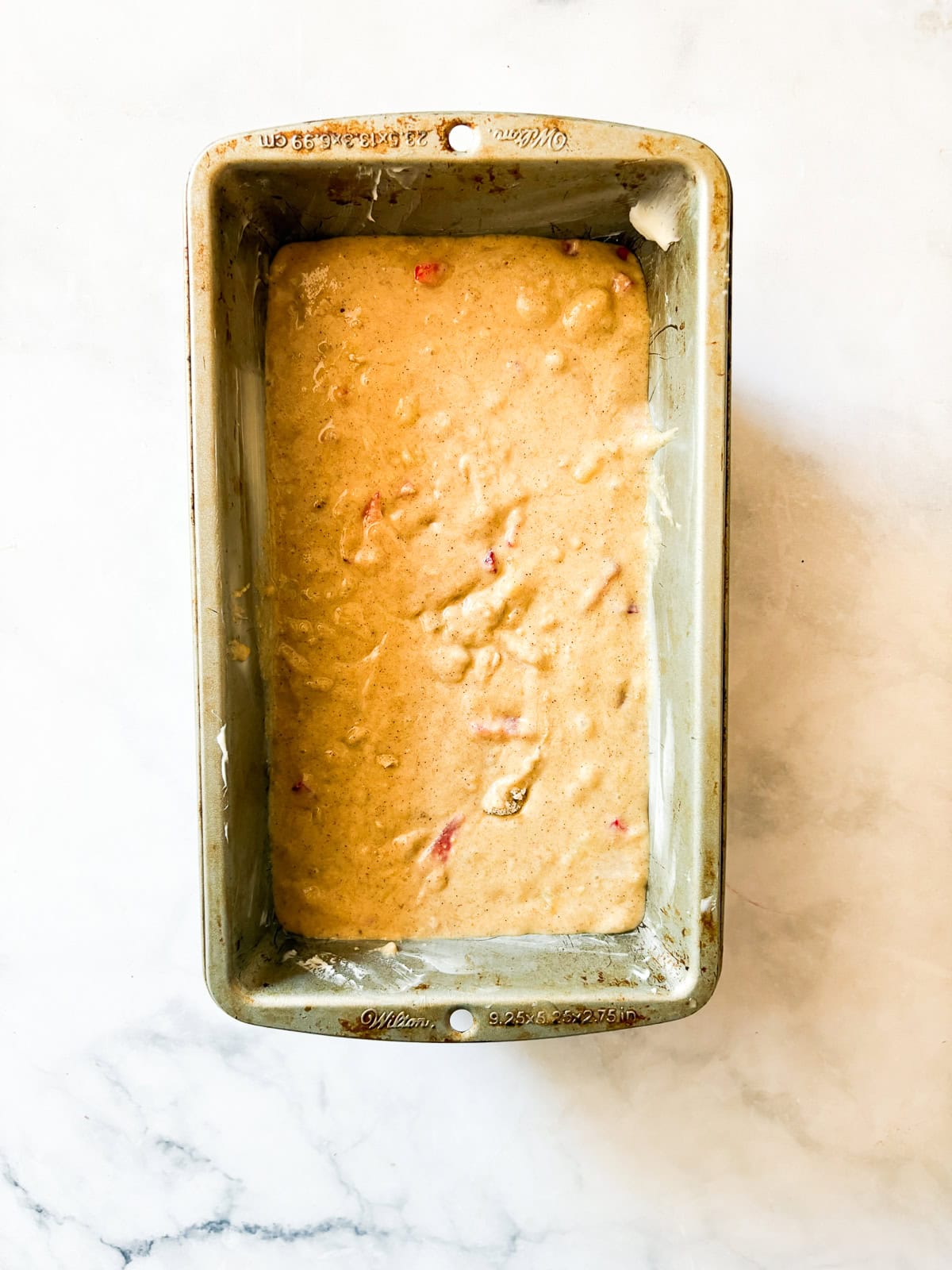 This one-bowl, gluten free easy banana strawberry bread comes together in minutes, and features plenty of chopped fresh strawberries and a kick of cinnamon. The batter for banana strawberry bread in a loaf pan.