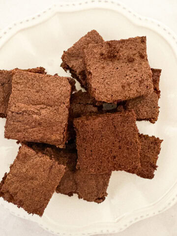 A nice pile of one bowl brownies served on a white plate.